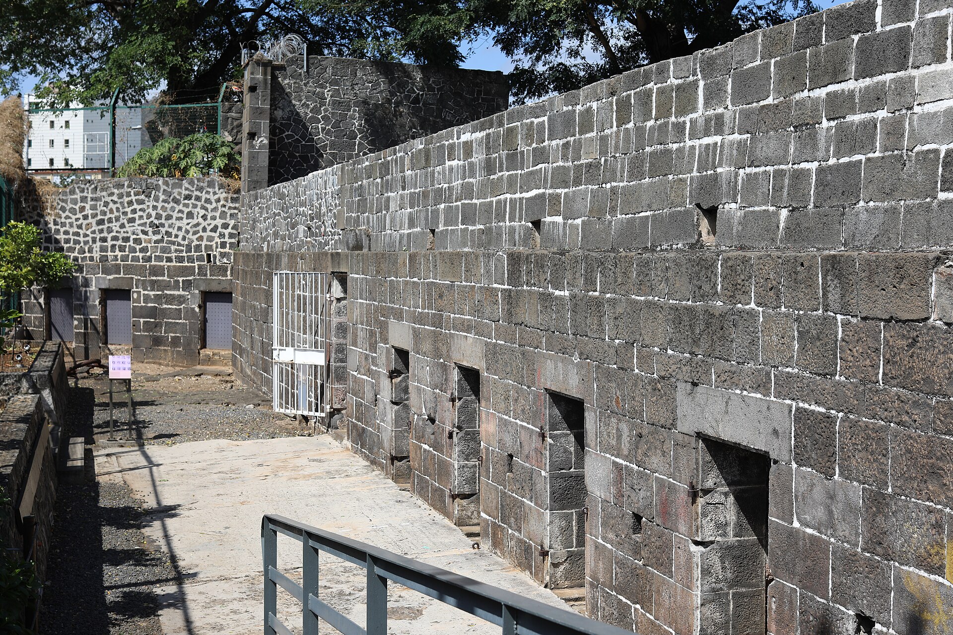 A long stone wall with openings, part of the surviving Aapravasi Ghat buildings in Port Louis.