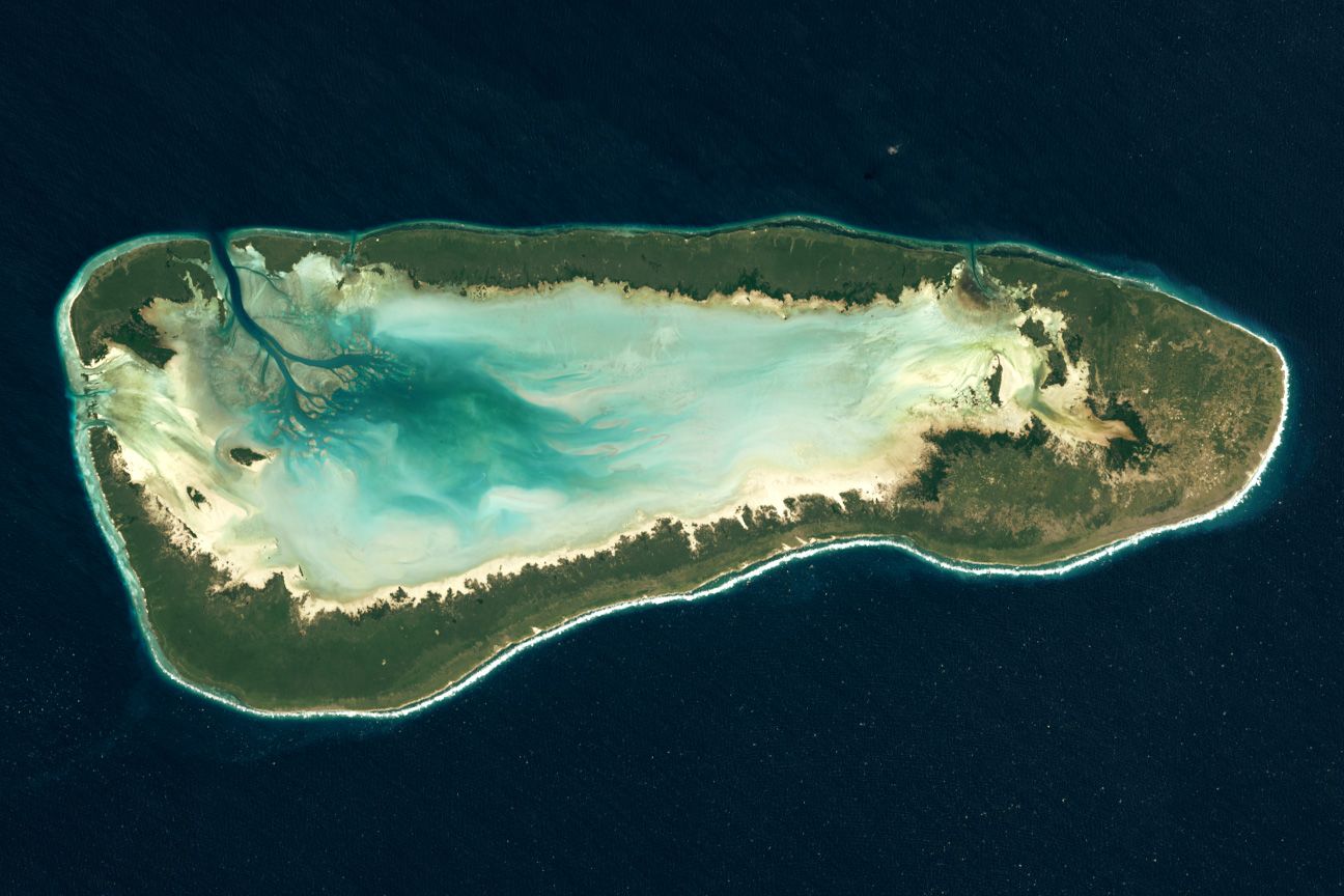 Satellite view of Aldabra: a long ring of land around a pale turquoise lagoon, in dark blue sea.
