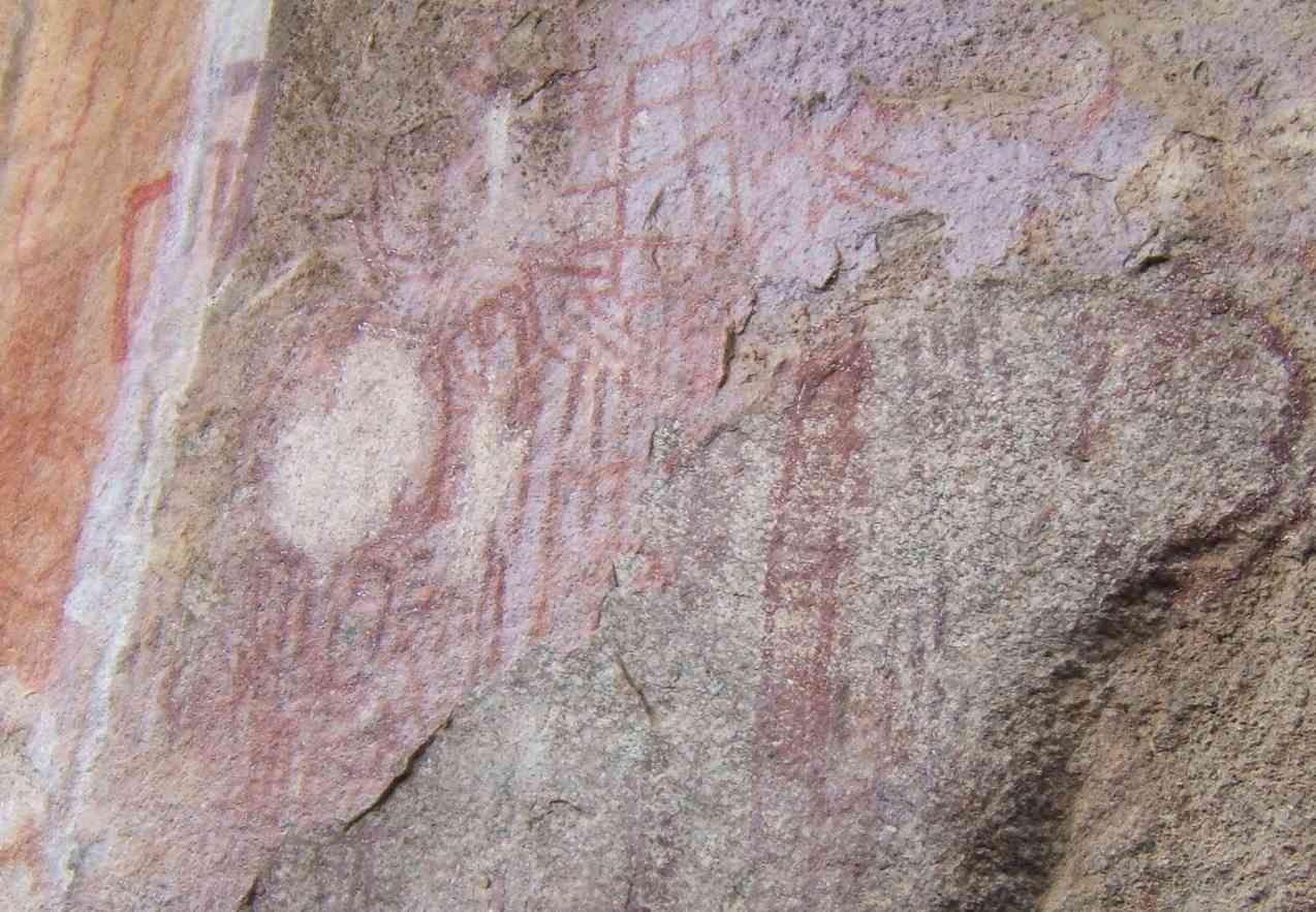 Faint red and white painted marks on pale rock, including a round shape.