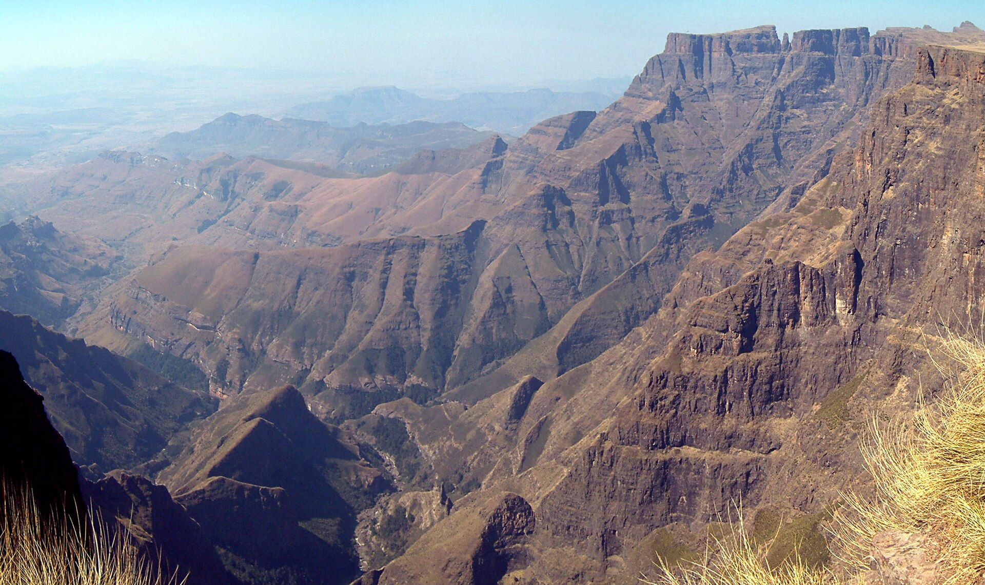 A deep valley below a long wall of basalt cliffs, seen from a high viewpoint.